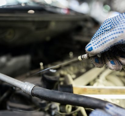 mechanic with dipstick checking motor oil level